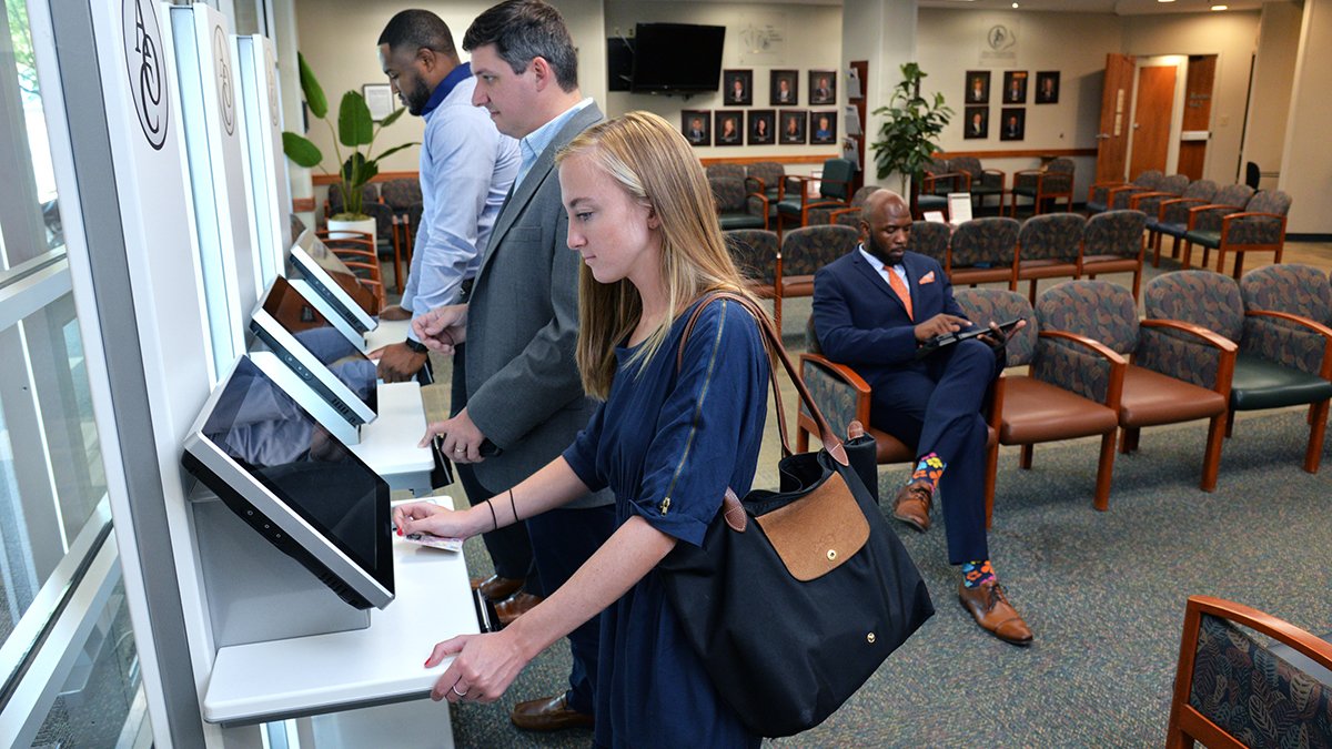 Patients using kiosks to check-in at a medical practice waiting room
